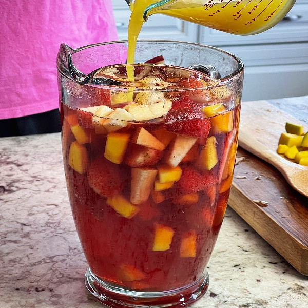adding orange juice to mocktail sangria