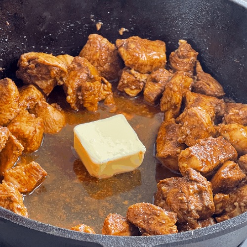 adding butter to garlic butter chicken