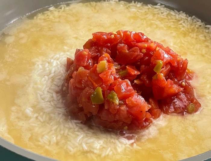 add rice, chicken broth and rotel tomatoes into hot skillet.