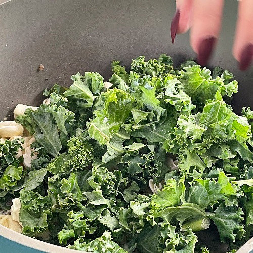 adding kale to creamy tortellini soup