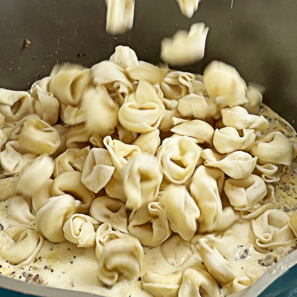 adding cheese tortellini to creamy tortellini soup