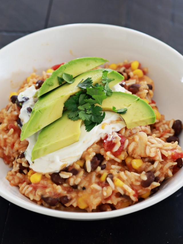 mexican chicken and rice in a white bowl with avocado slices on top