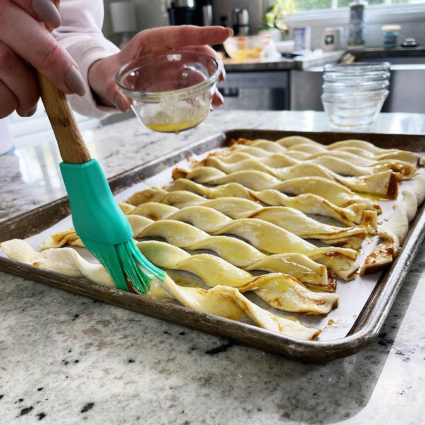 spreading melted butter on pumpkin pie twists before baking