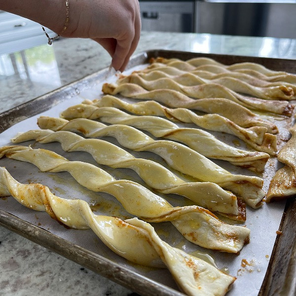 sprinkling cinnamon sugar on pumpkin pie twists before baking