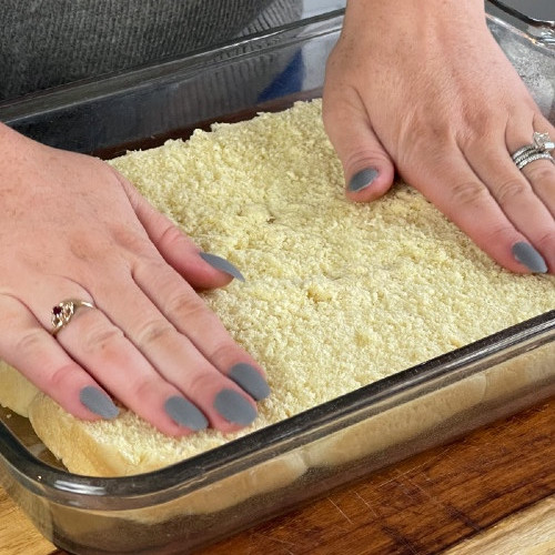 Setting bottom layer of Hawaiian rolls into baking dish