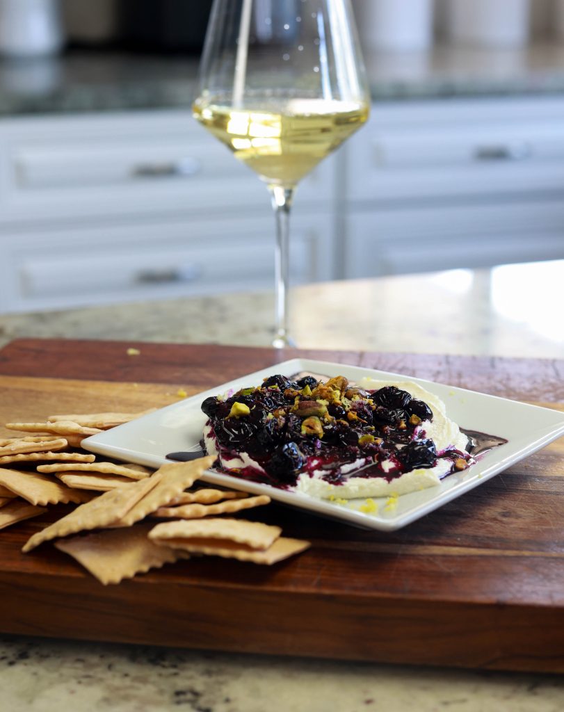 A crisp glass of Chardonnay paired with whipped goat cheese and a blueberry compote