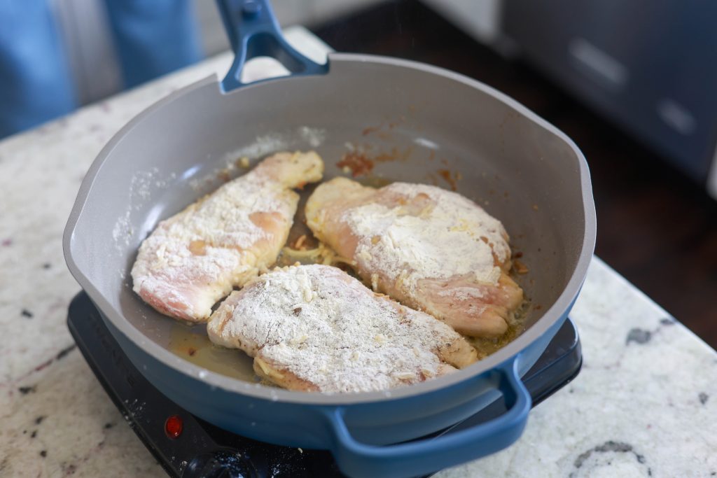 Irresistible Creamy Garlic Chicken Skillet Recipe 2 Flour dredged chicken pan frying for dinner.
