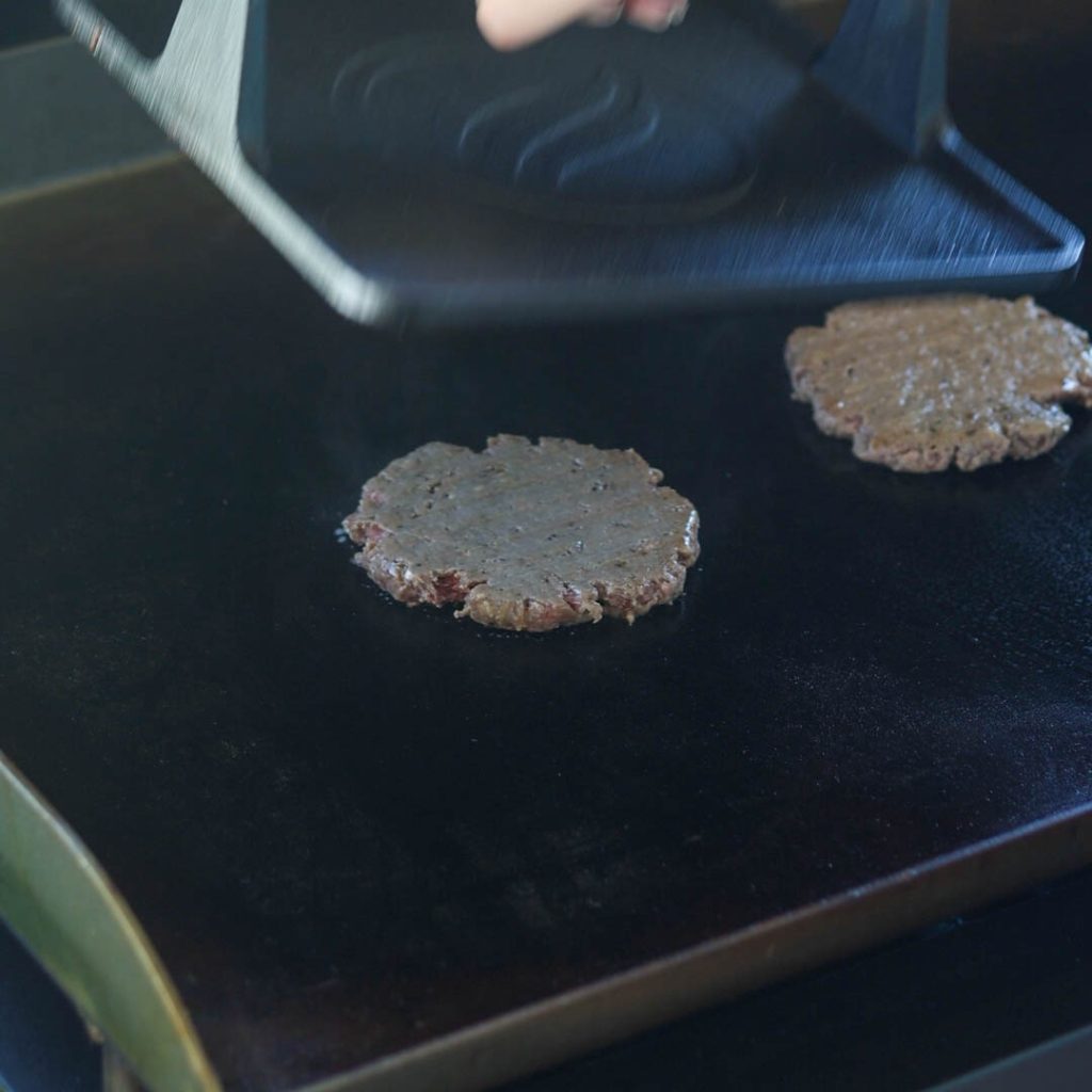 smashing burgers on the blackstone grill with griddle press