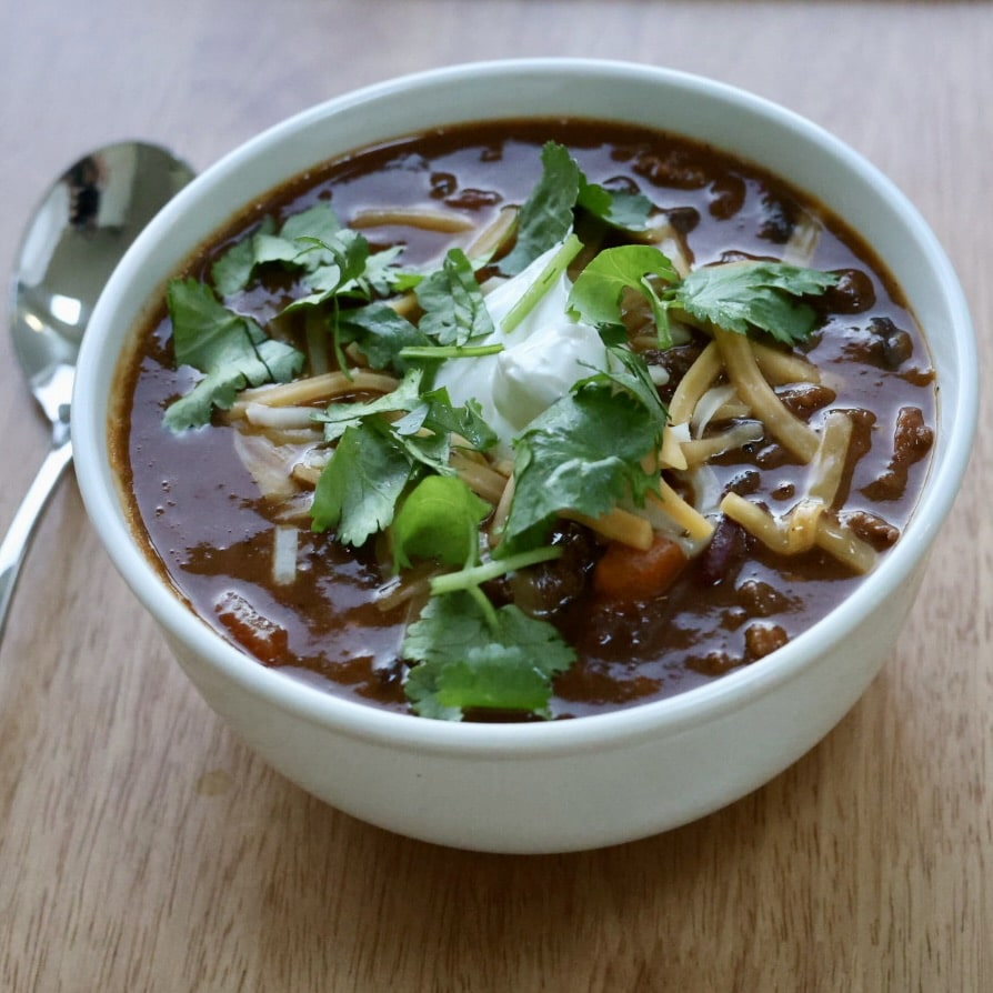 Bowl of pumpkin chili with toppings