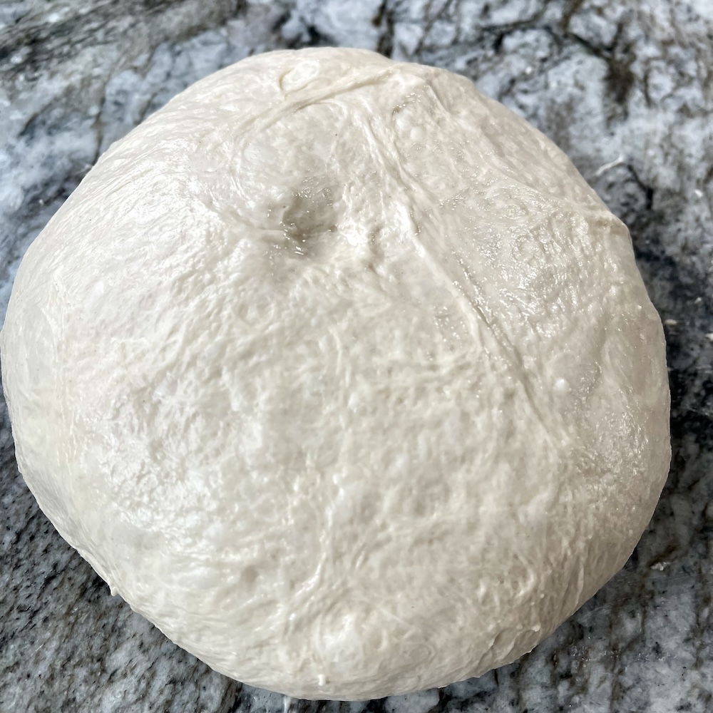 How to Proof Sourdough Bread: Timing, Temperature, and Signs of Under/Overproofing 7 Poke test on proofed sourdough dough showing a slow-spring indentation.