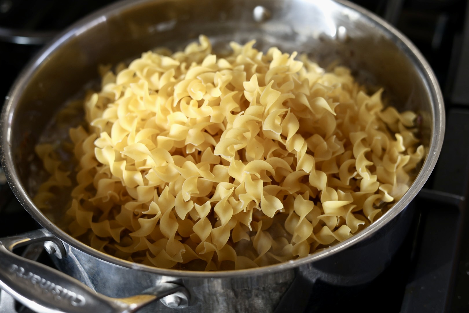assembling creamy ground beef stroganoff with egg noodles in a skillet