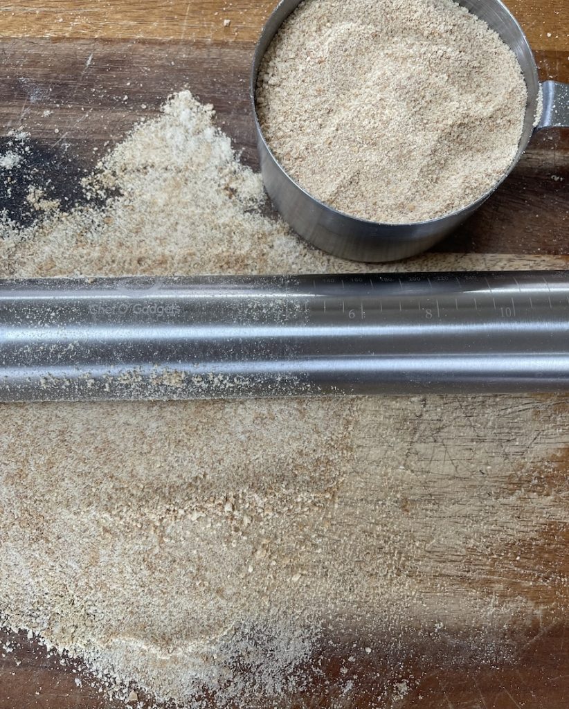 crushing graham cracker fine. graham crumbs on a board with rolling pin