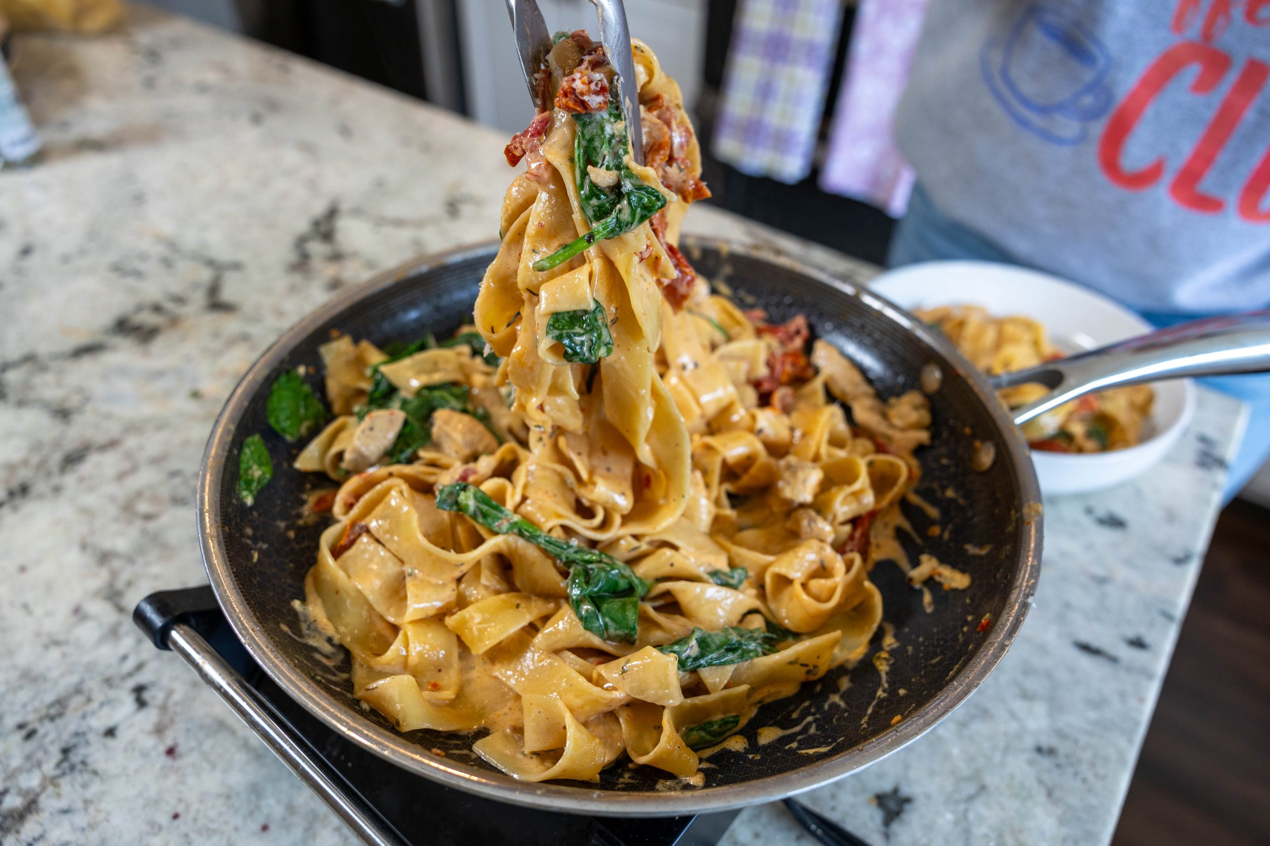 Creamy garlic chicken noodles being pulled from a skillet