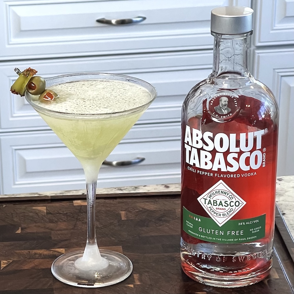 absolut tabasco vodka martini with a bottle of absolut tabasco vodka on a dark board. white kitchen background