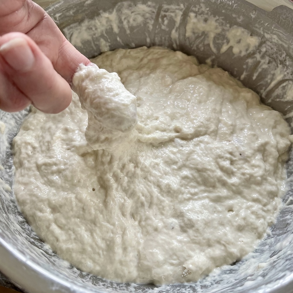 bassinage begins with a dough already somewhat developed. adding extra water initially loosens the dough structure.