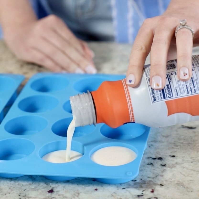 how to freeze heavy cream. pictured is Kayti pouring heavy cream into ice cube trays.